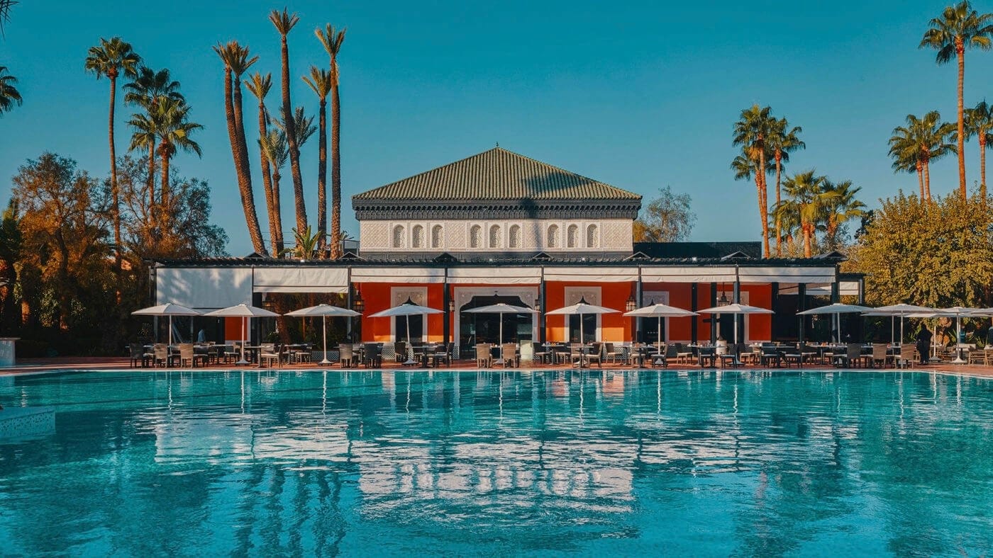 Swimming in front of large dining area with seats outside and large orange building