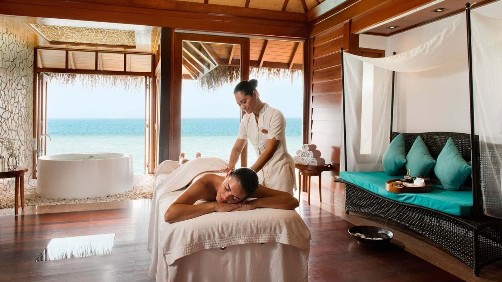 Woman being massaged in spa room with bathtub at Constance Halaveli.