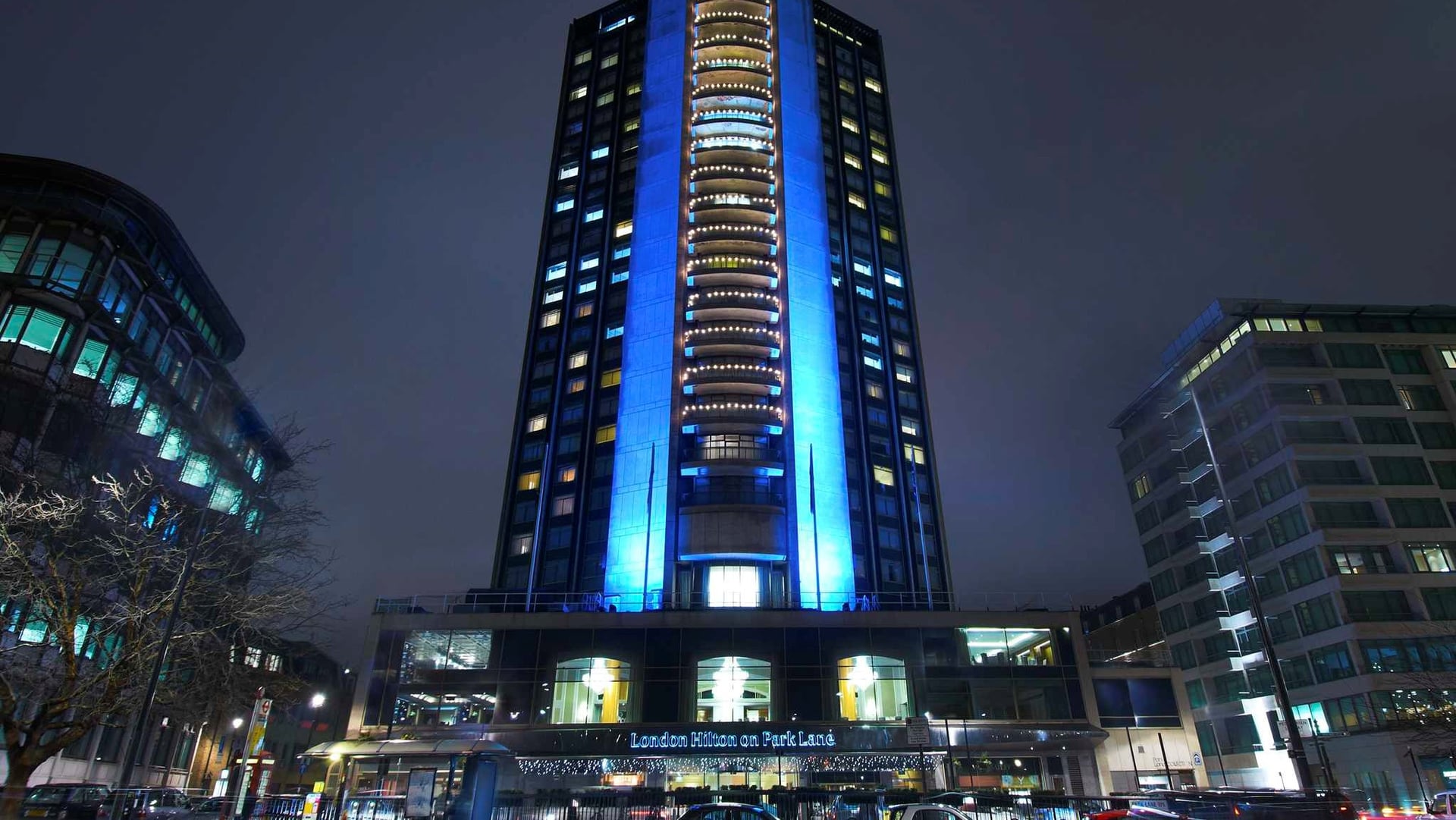 Front entrance of the tall london hilton hotel on park lane with blue neon lights.