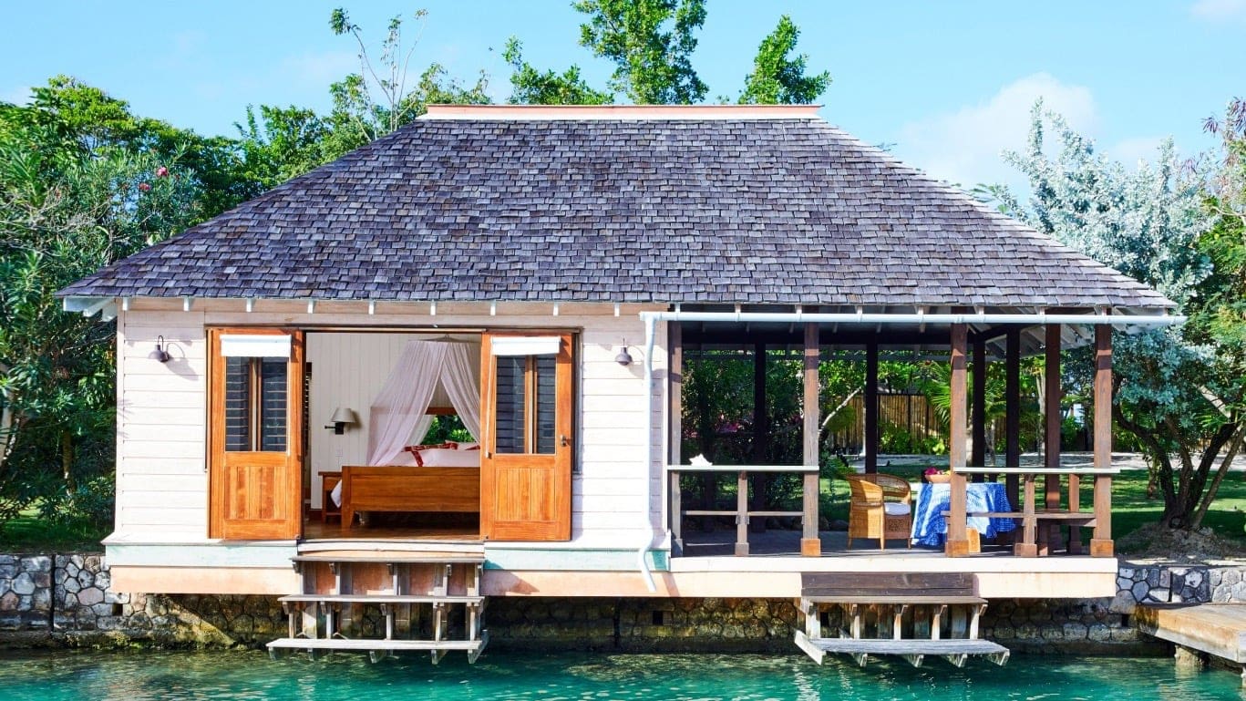 Outside of view of white cabin with outside area and staitway to thye water.