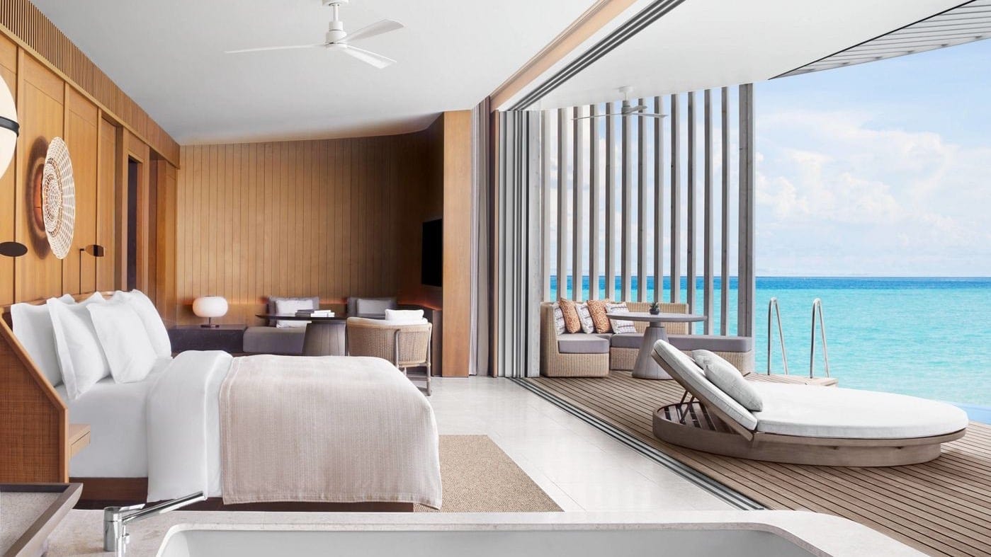 Suite at The Ritz-Carlton Maldives, Fari Islands with kingsize bed, sunbeds and direct ladder to ocean.