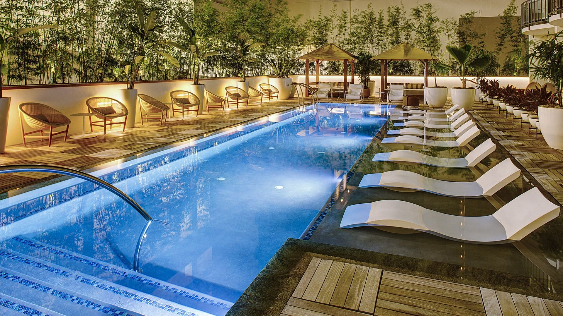 Pool area with sunbeds, and gold glowing chairs at The Laylow Autograph Collection.
