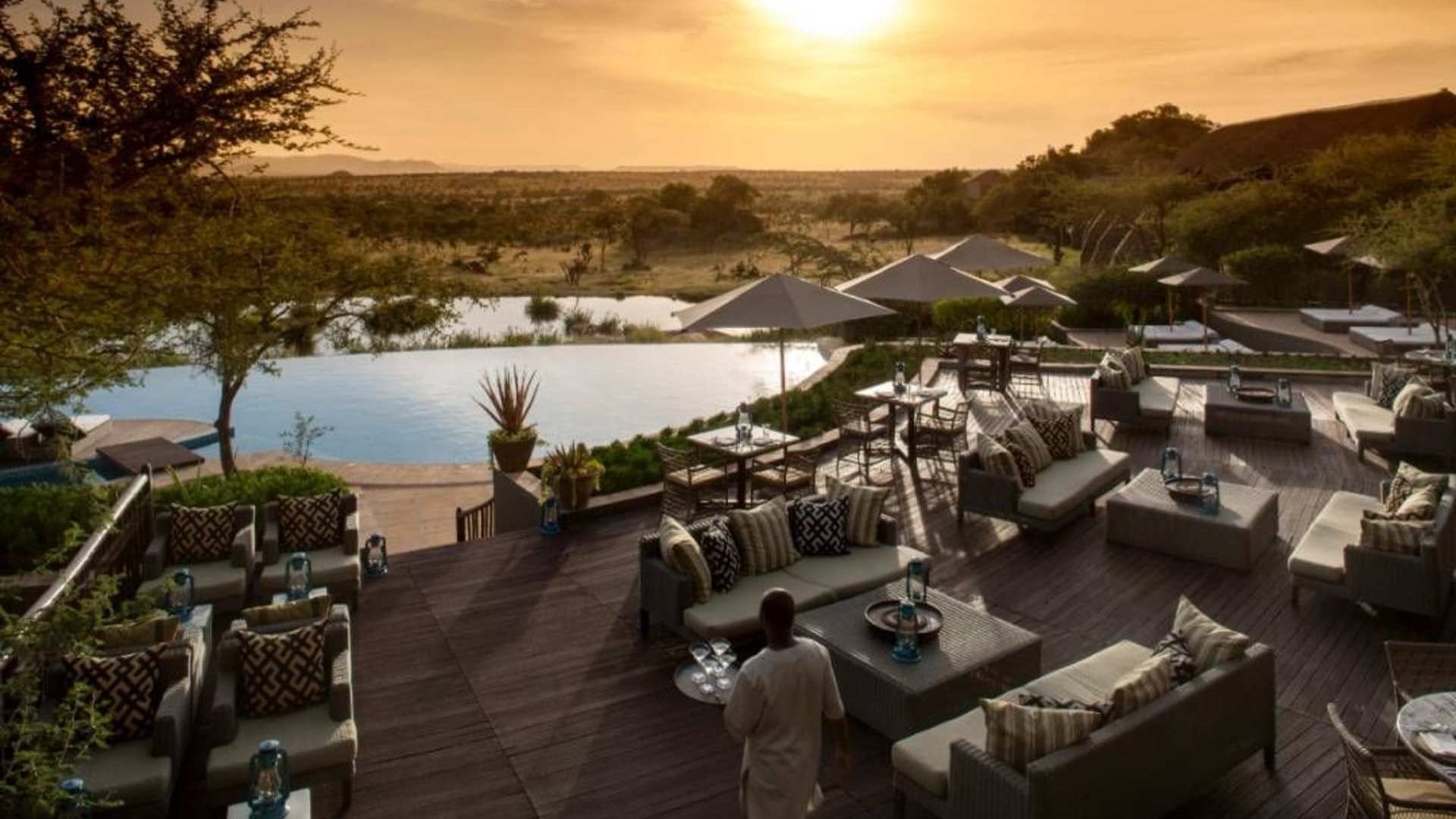 Multiple couches and chairs facing the savvanah with sunset and a private pool