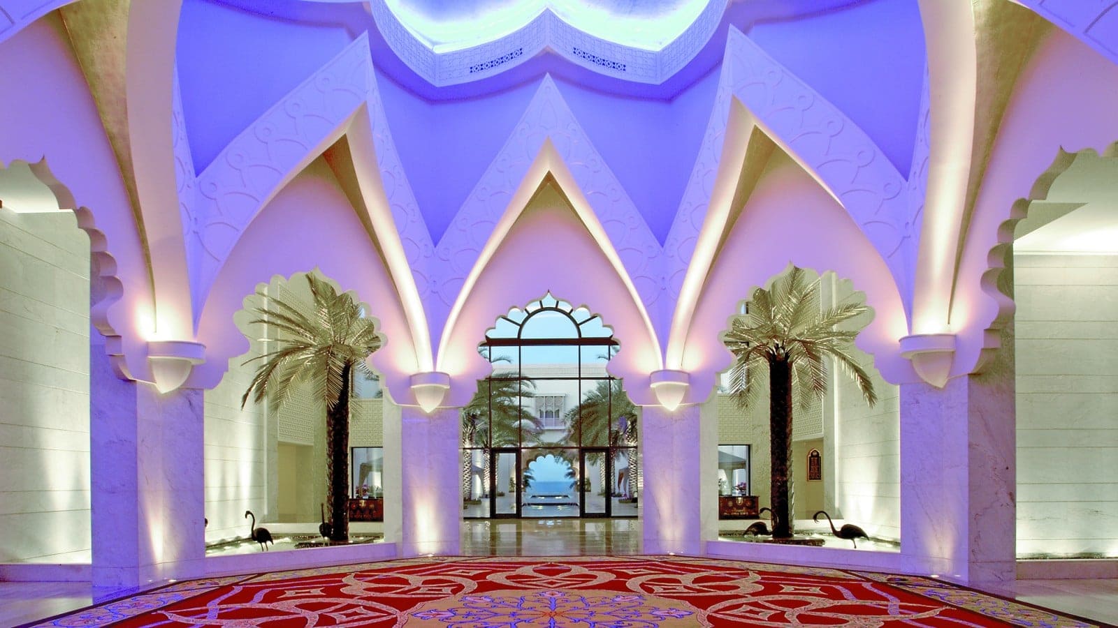 Red, yellow and blue pattern floor with flowers in the median, tall white marble walls and a view to the ocean