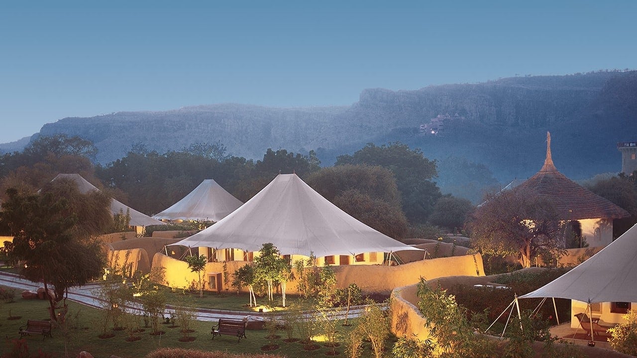 Bird view of four white camps and a brick building turning night time with nature and lighting.