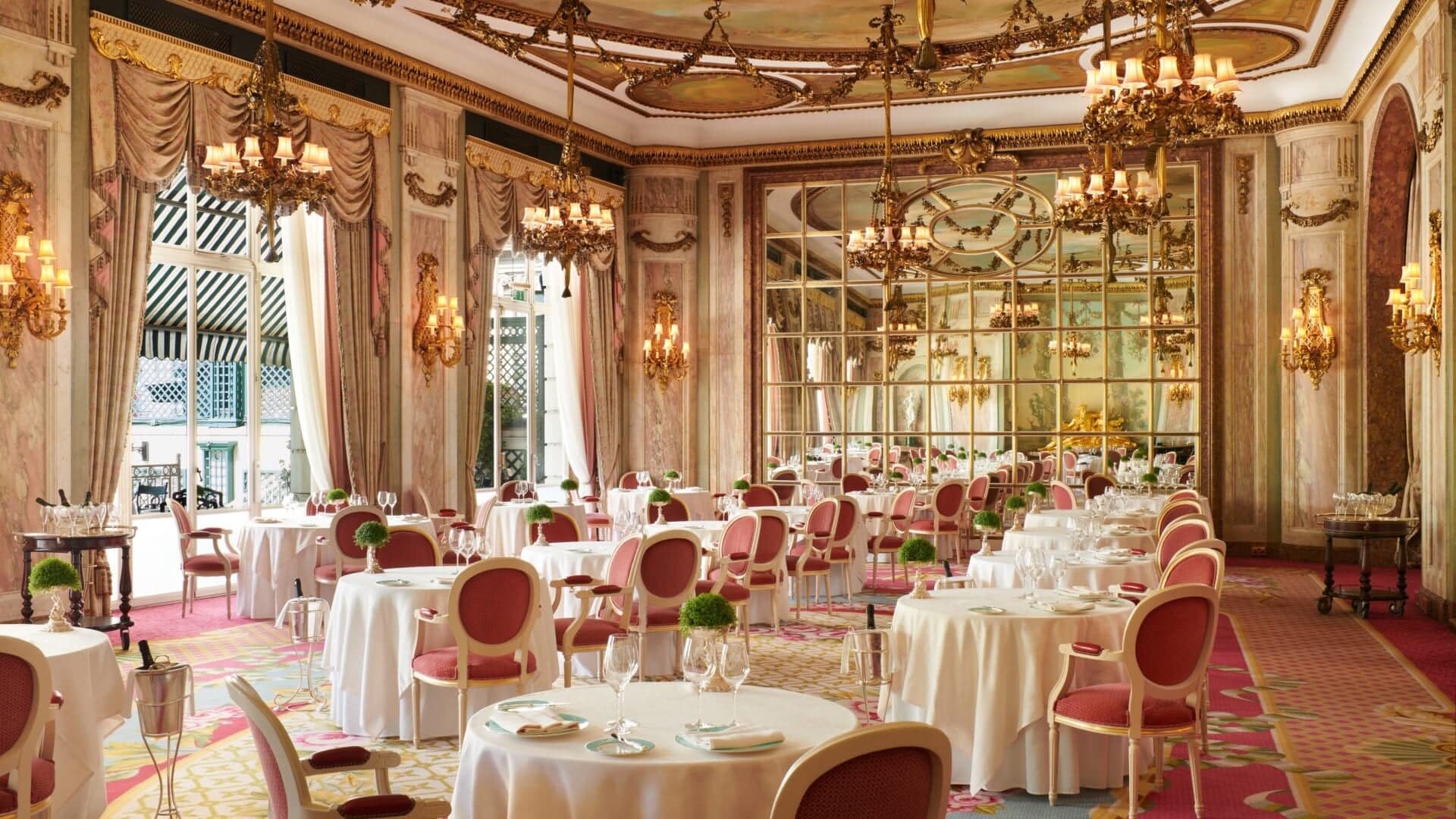 Inside dining area at The Ritz with large mirrors, pink and white design and golden and marble wall and ceiling decor.