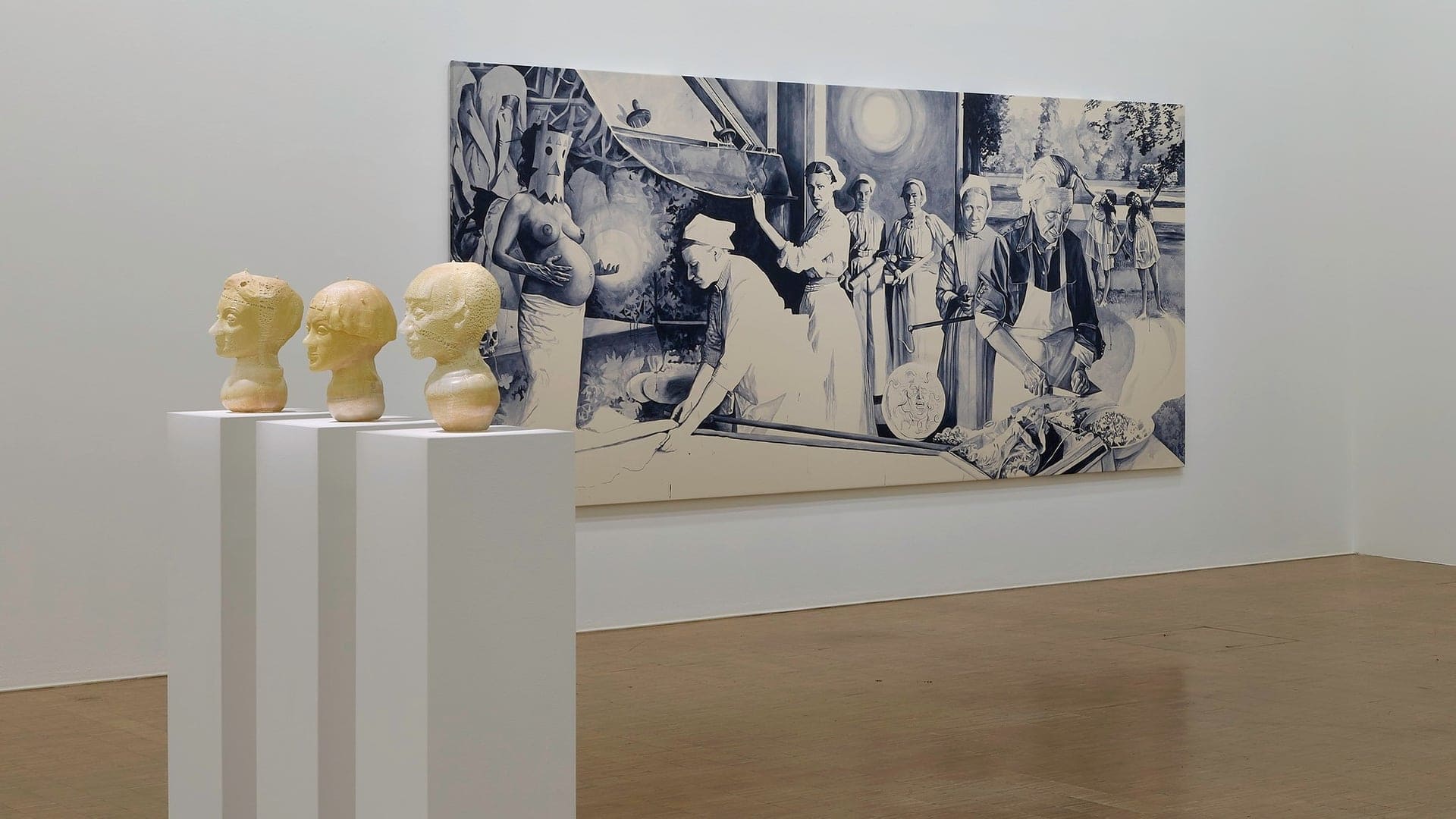 Inside the Accueil - Centre Pompiduo with three statue heads and painting on a white wall.