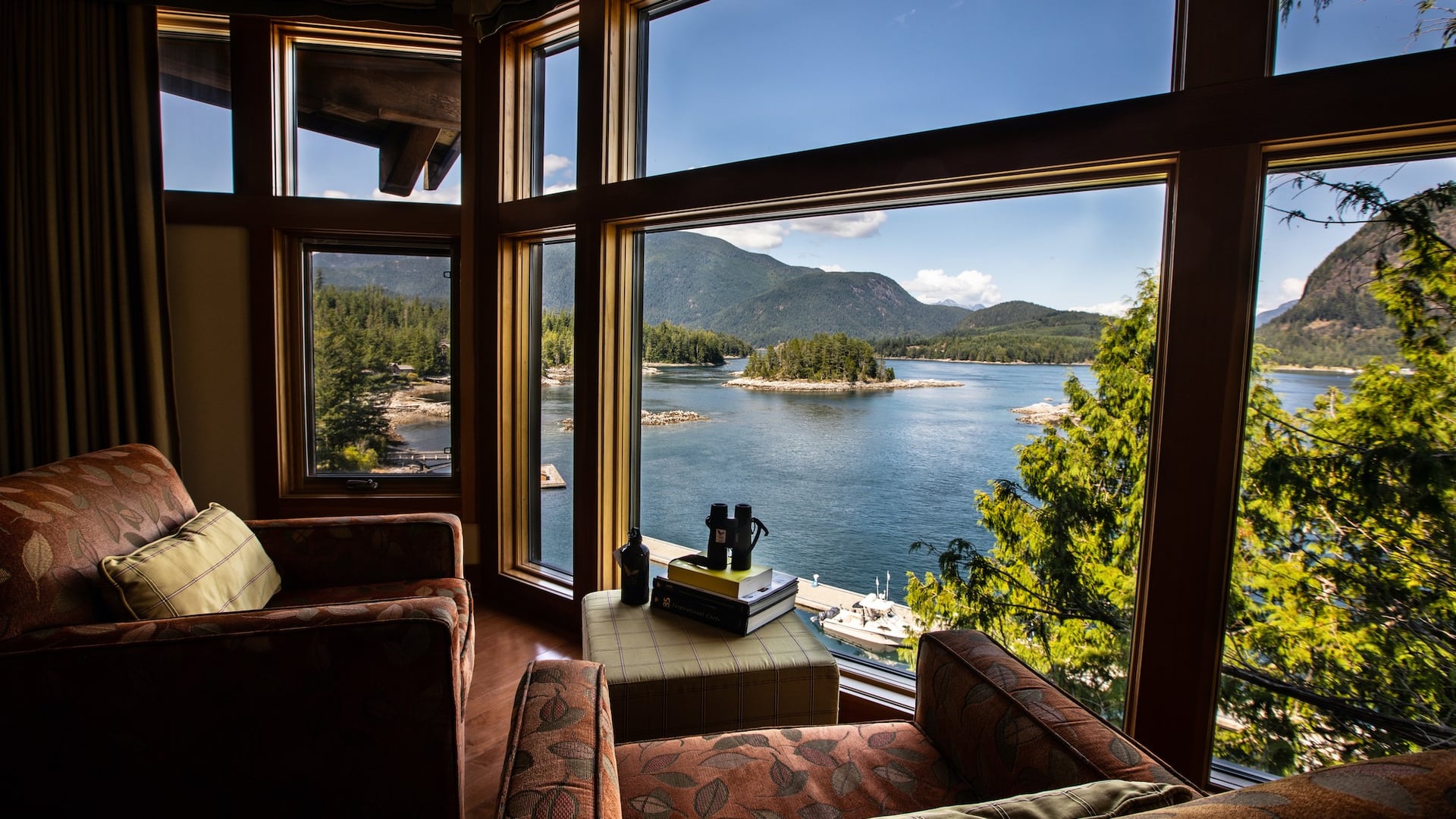 Two chairs facing a river and nature through large windows