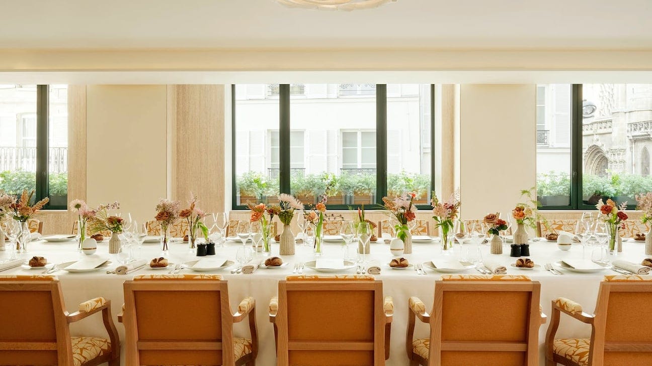 Big oval table with brown chairs and white walls at Plenitude paris