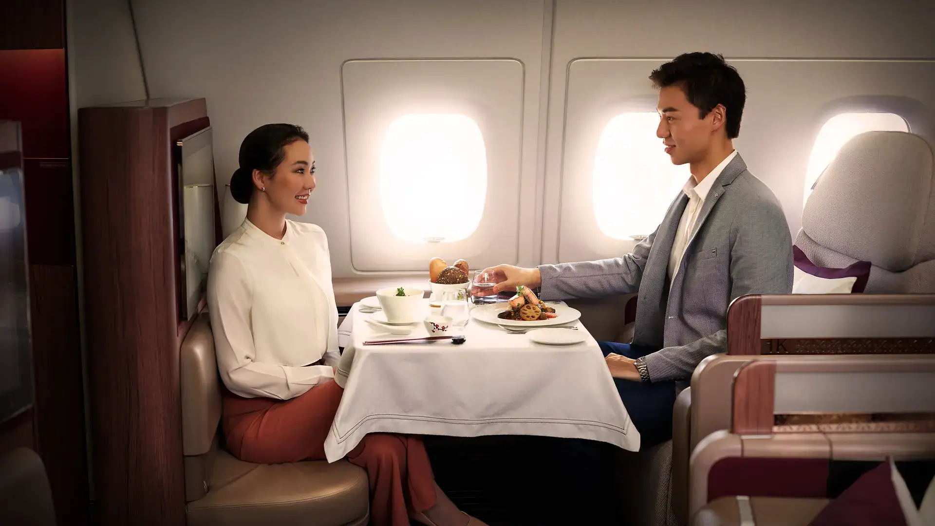a couple having lunch in qatar airways first class - one of the best first class airlines in the world