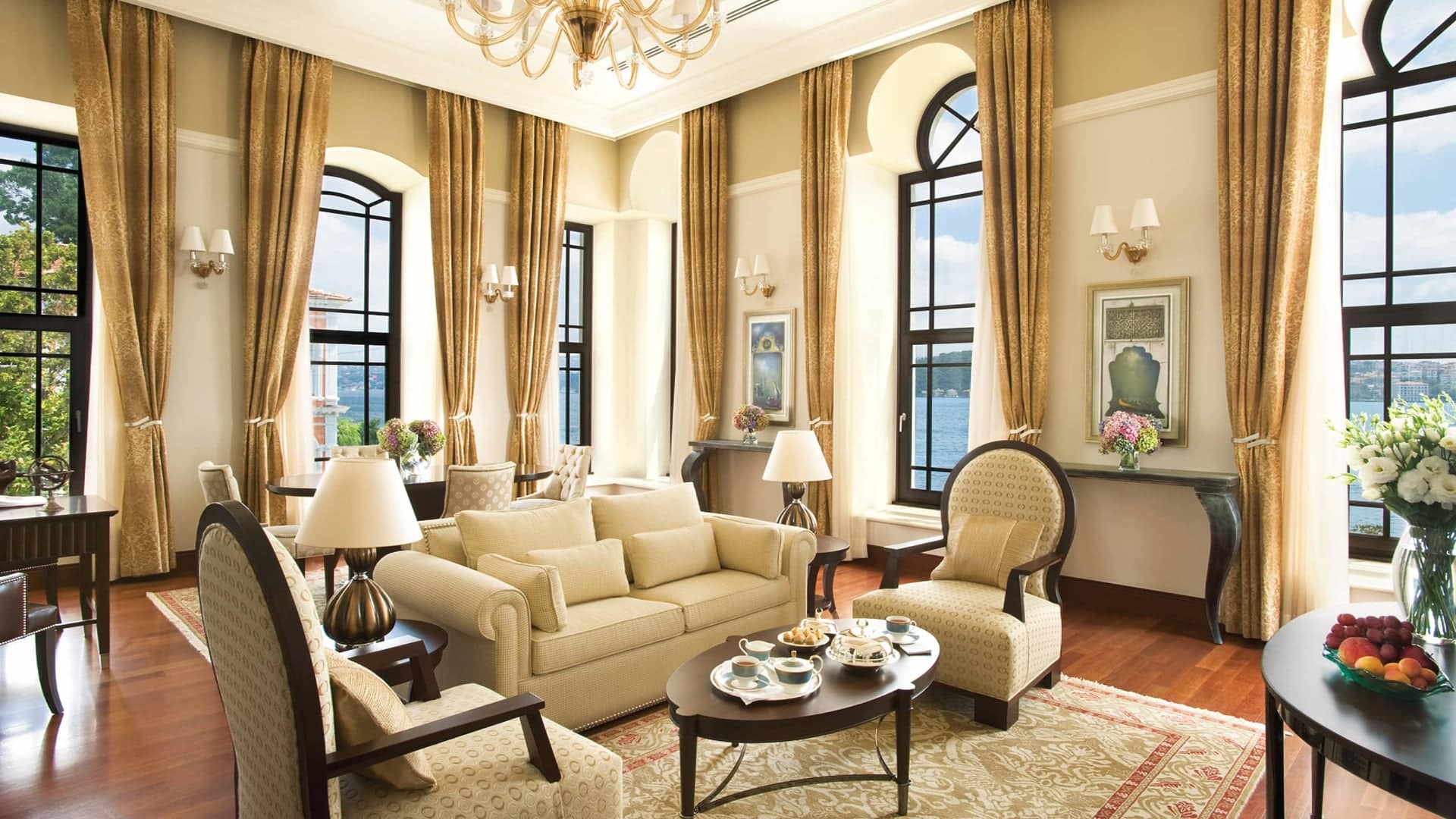 Suite at The Exquisite Four Seasons Istanbul At The Bosphorus offering a spacious living room with a comfortable interior design, couches and grand windows offering sights of the river and garden