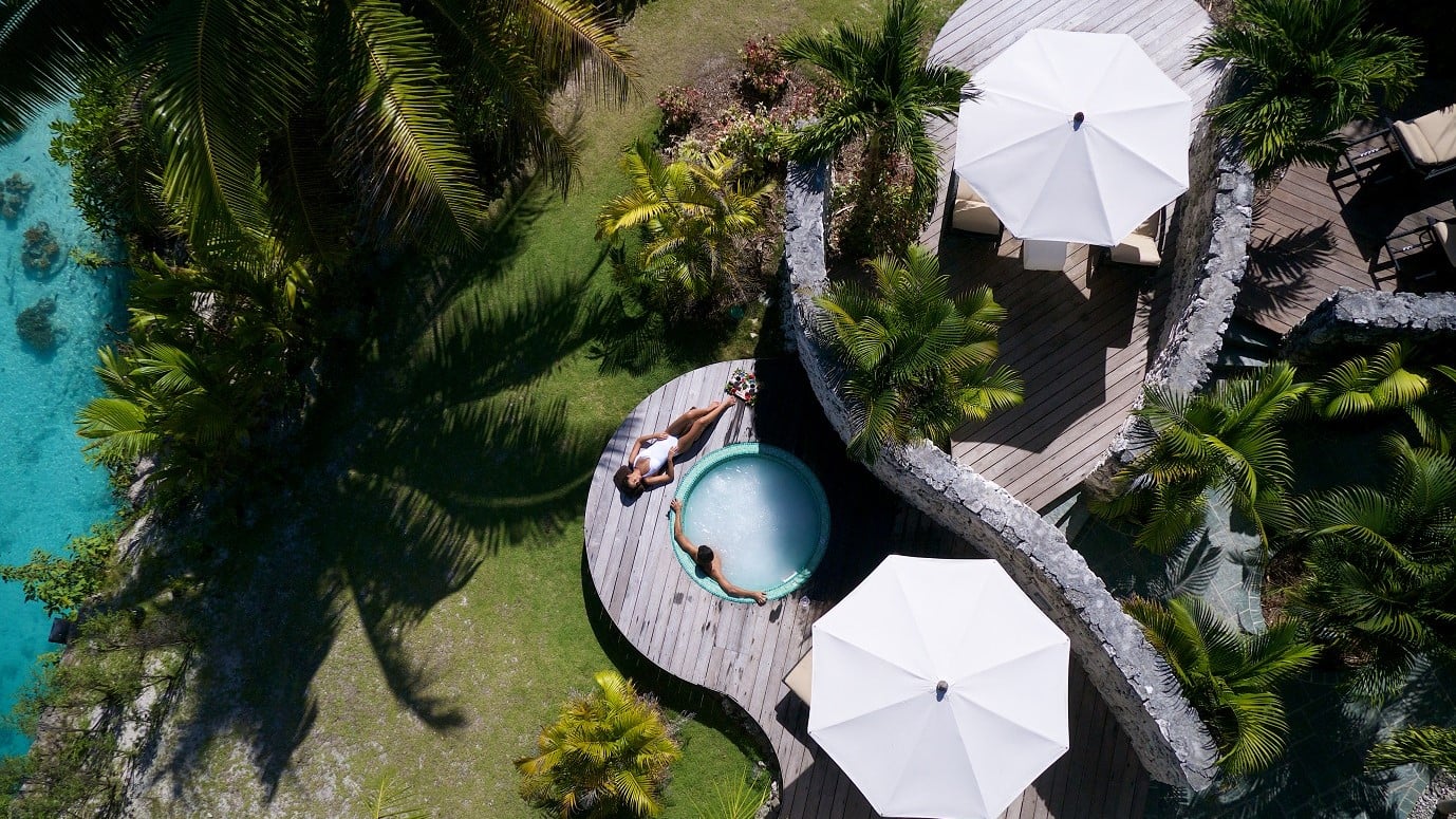 Bird perspective of a woman in white bathing suit, man in a jazzuzi and surrounded by nature in InterContinental Bora Bora Resort