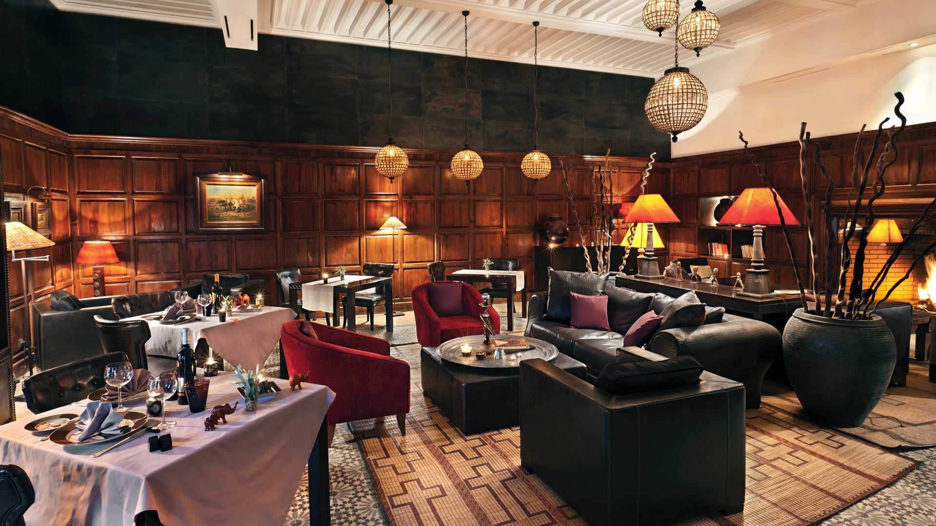 A resturant with a black sofa lounge in center, black tables with chairs. wooden square shaped walls.