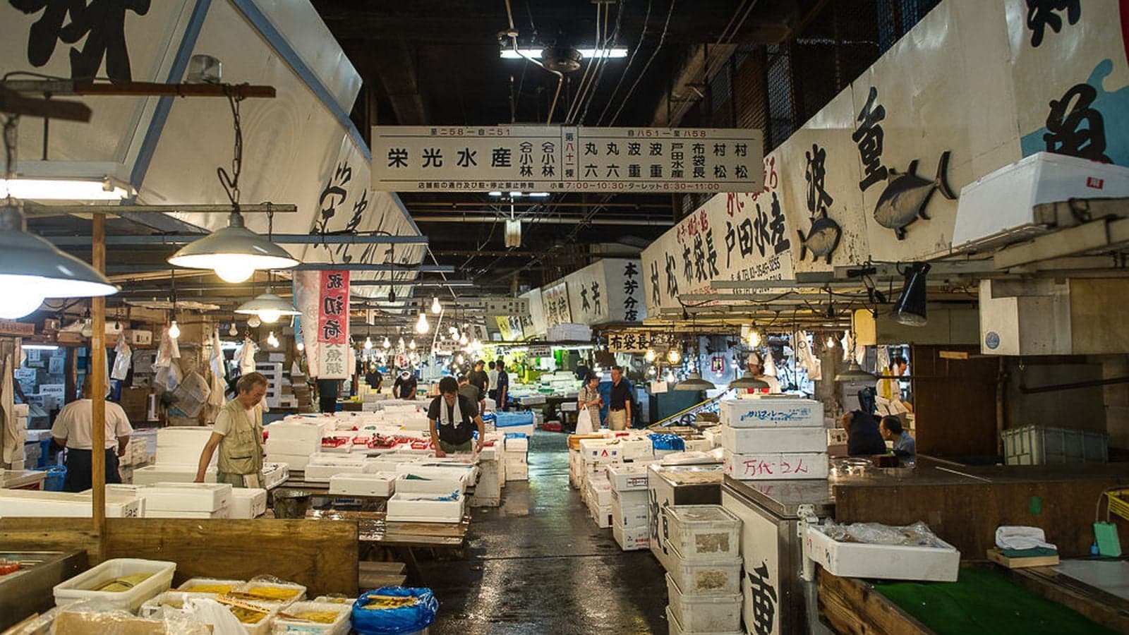 Fish market in Tokyo, with white signs, fish, and employyes calles Tsukjii Fish Market in Tokyo.