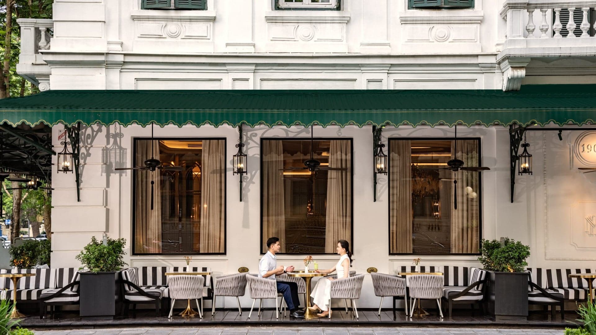 a couple sitting for luch outside Sofitel Legend Metropole Hanoi