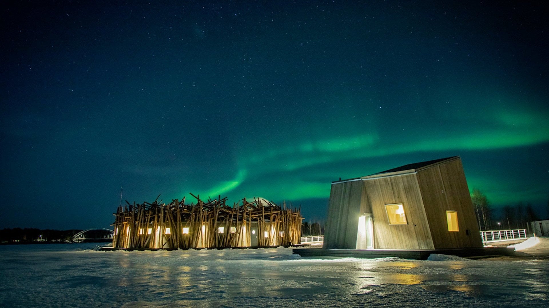 A outside hotel made of wood near the ice under the northern lights.