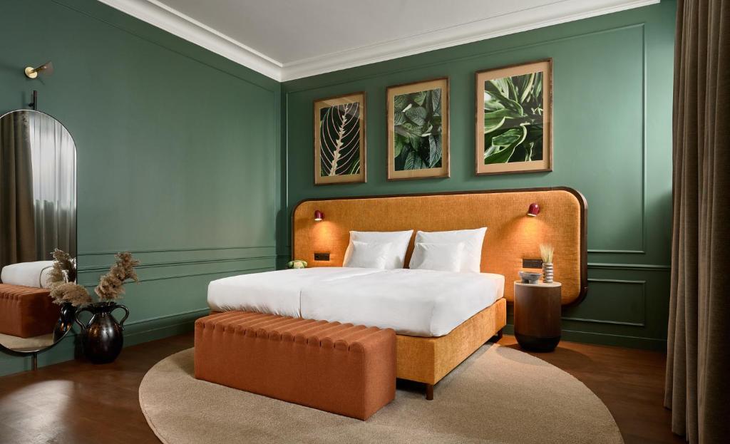 Hotel room at Verno House with green walls, plant paintings, orange decored bed.