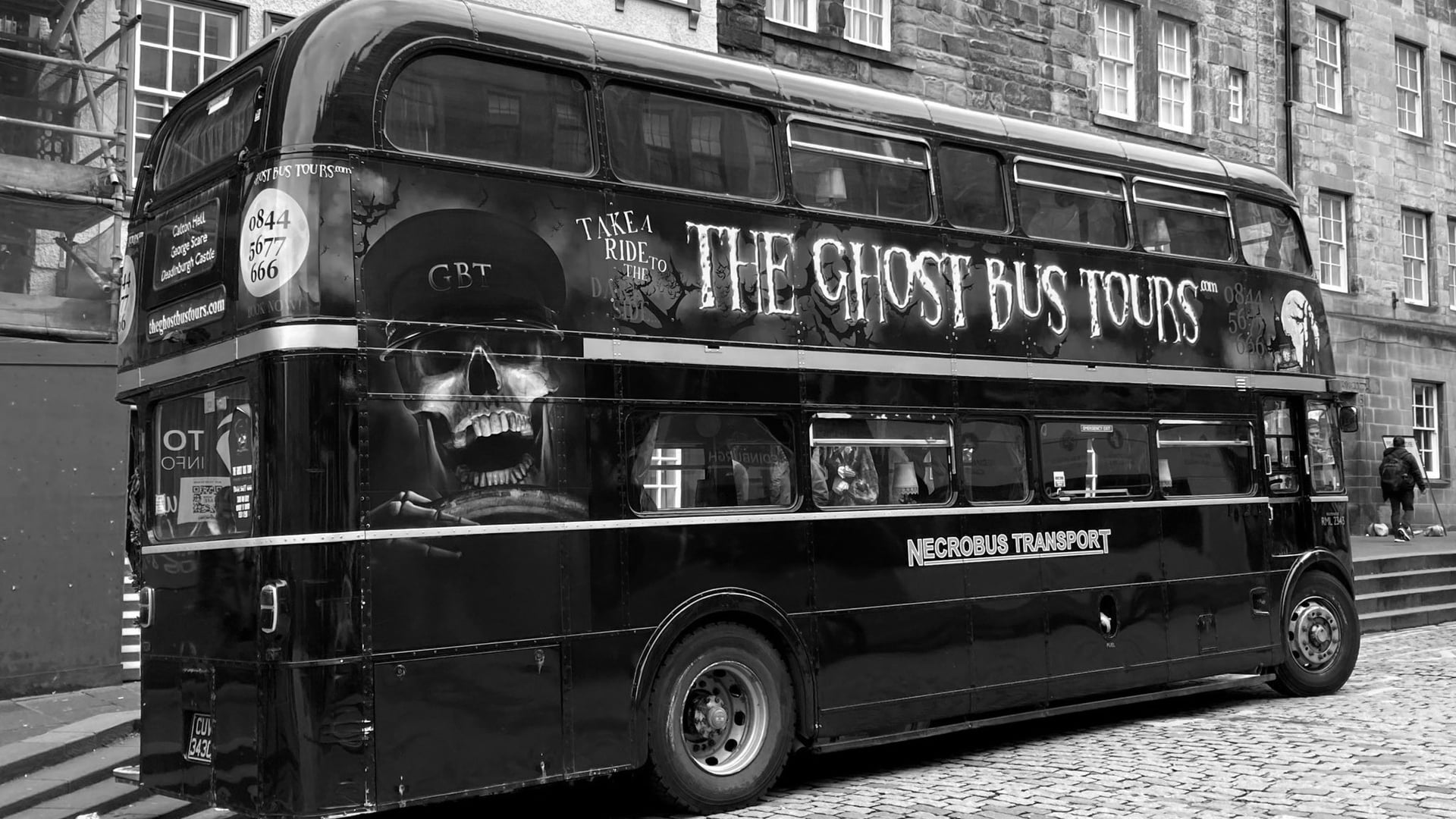 Black and white colour of a bus saying: THE GHOST BUS TOURS, and a illustration of a skeleton buss driver in Edinburgh, Scotland.