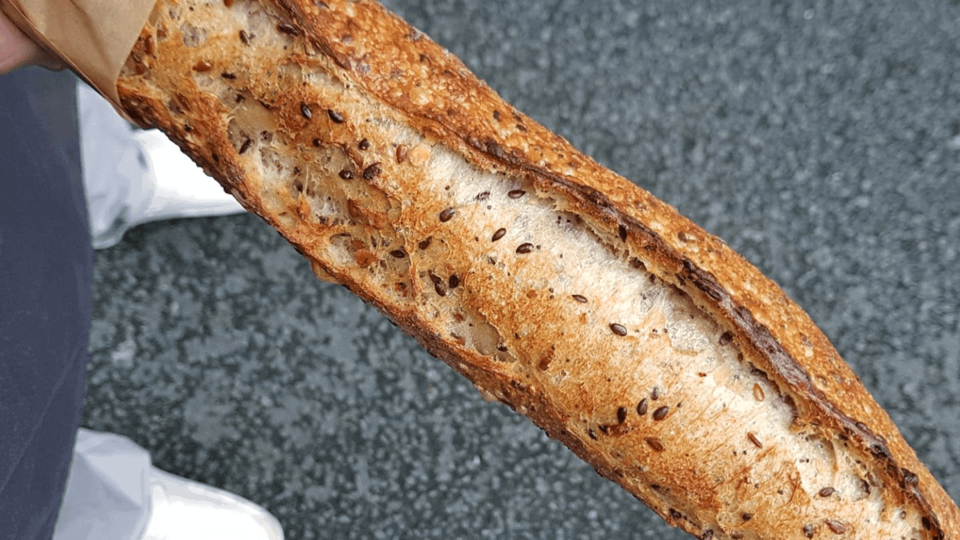 Baugette bread being held in the street made in Boulangerie Utopie Paris