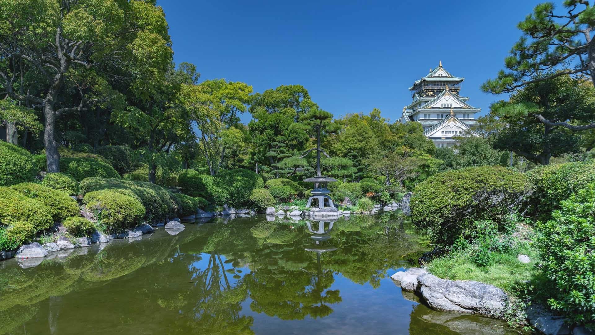 A moisty lake, stone fountain, nature on all sides and behind a temple looking building in white.