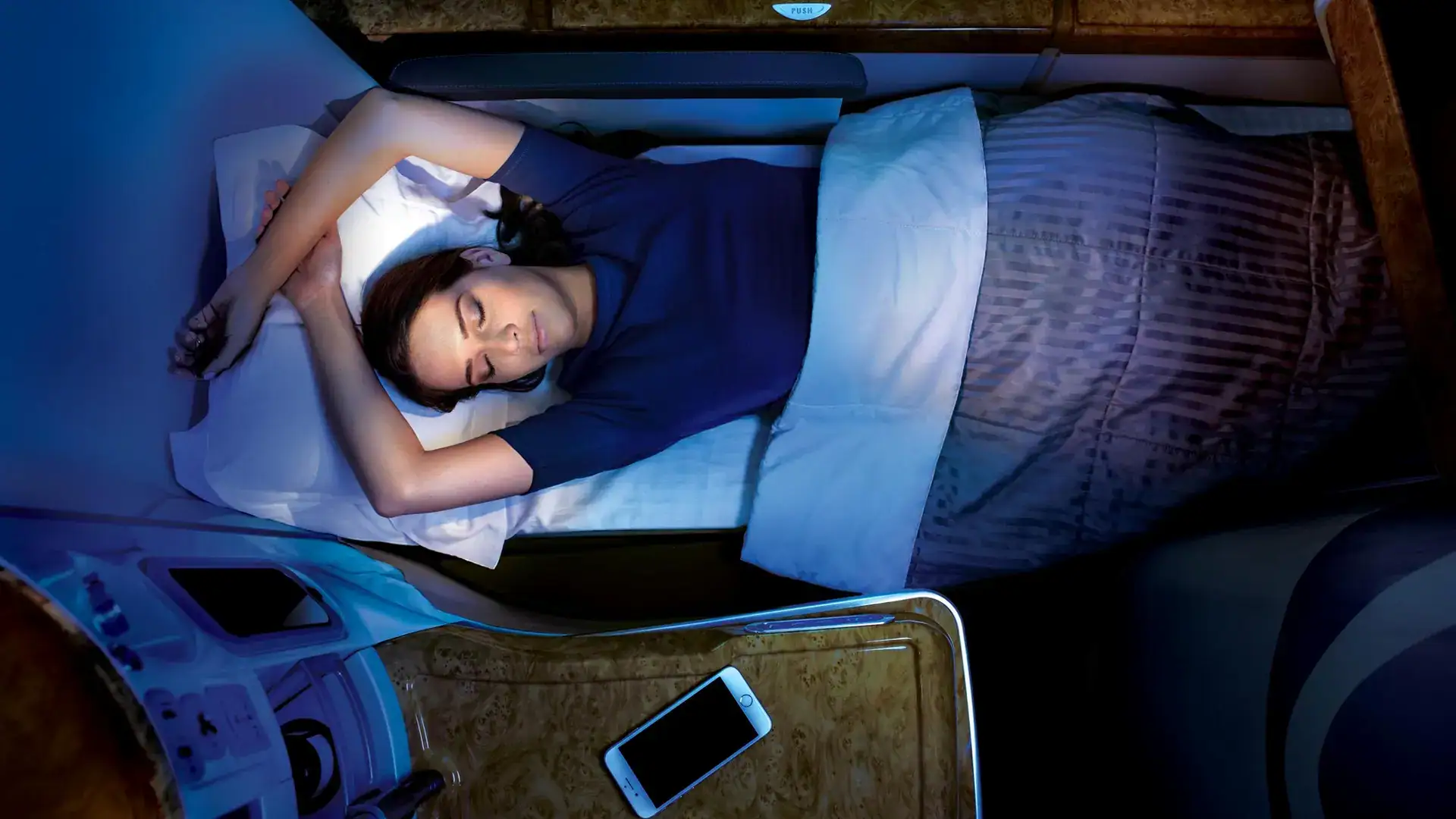 a woman sleeping in her emirates business class seat