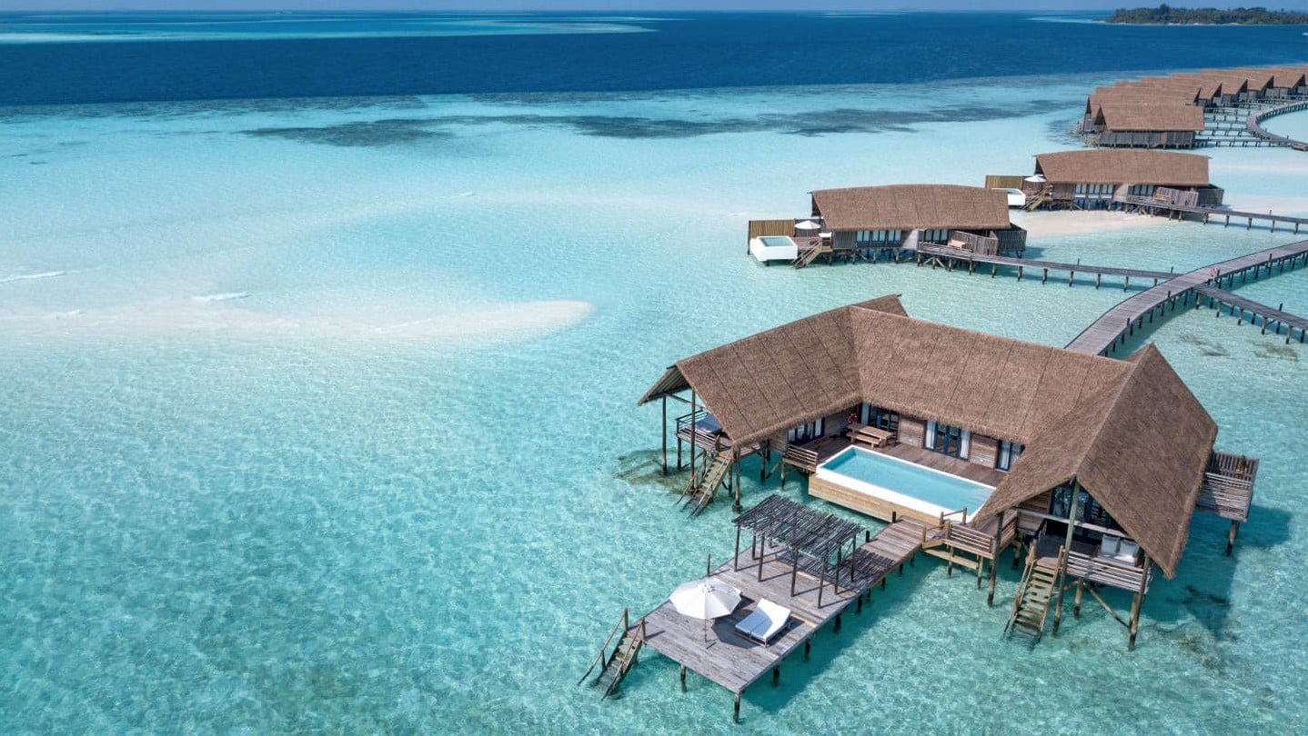 Crystal clear maldives water with multiple on water suites with pools, staircase to water.