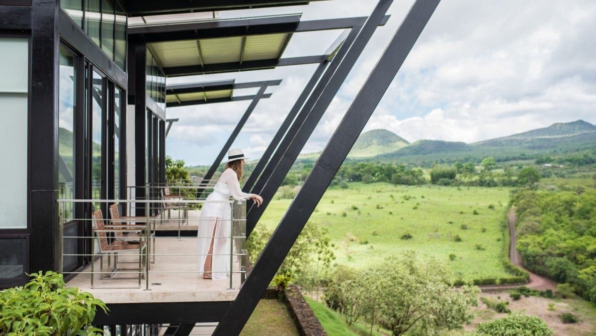A woman dressen in white looking at the nature from a terrace in black