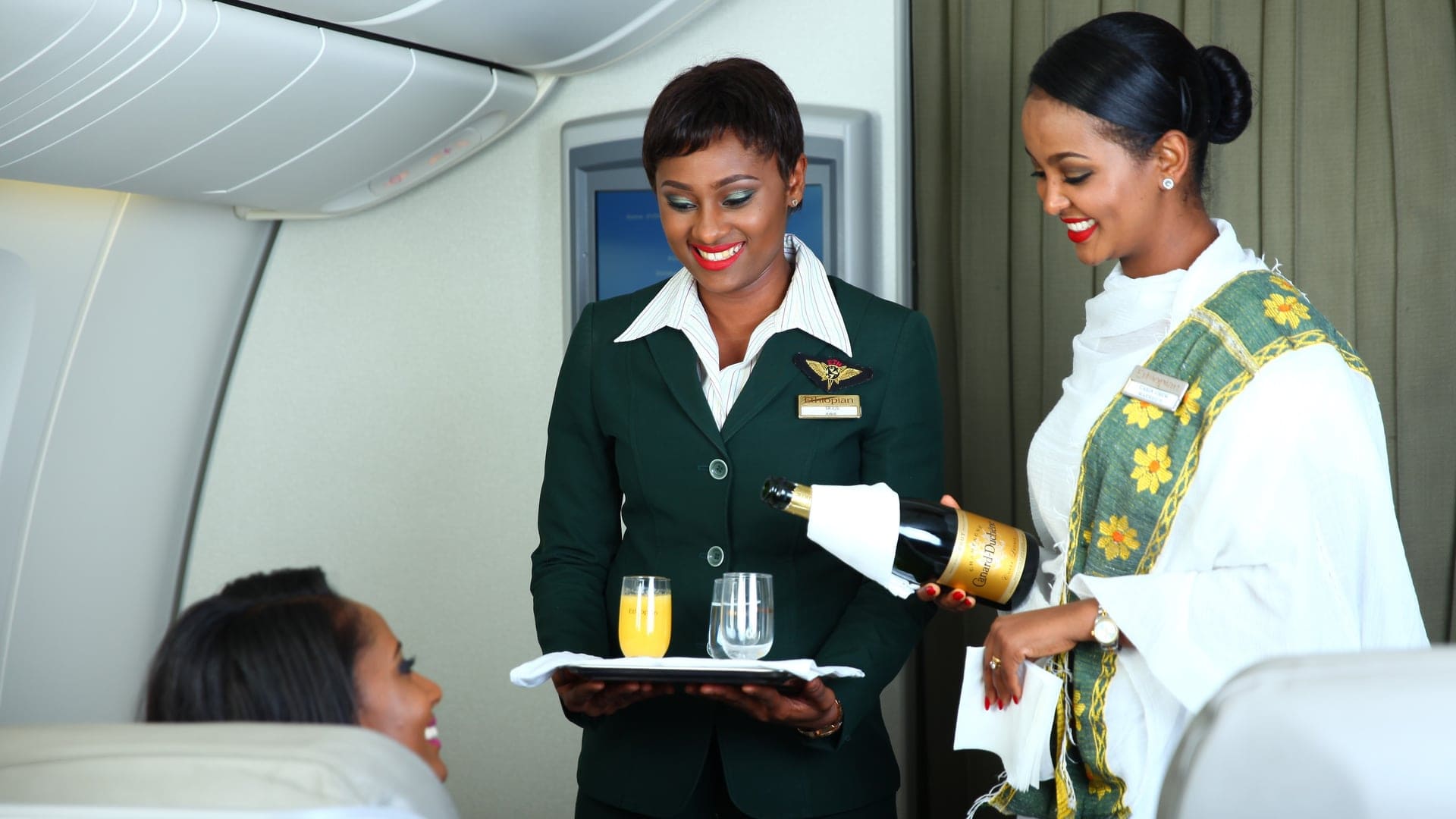Two women working on the plane serving champagne 