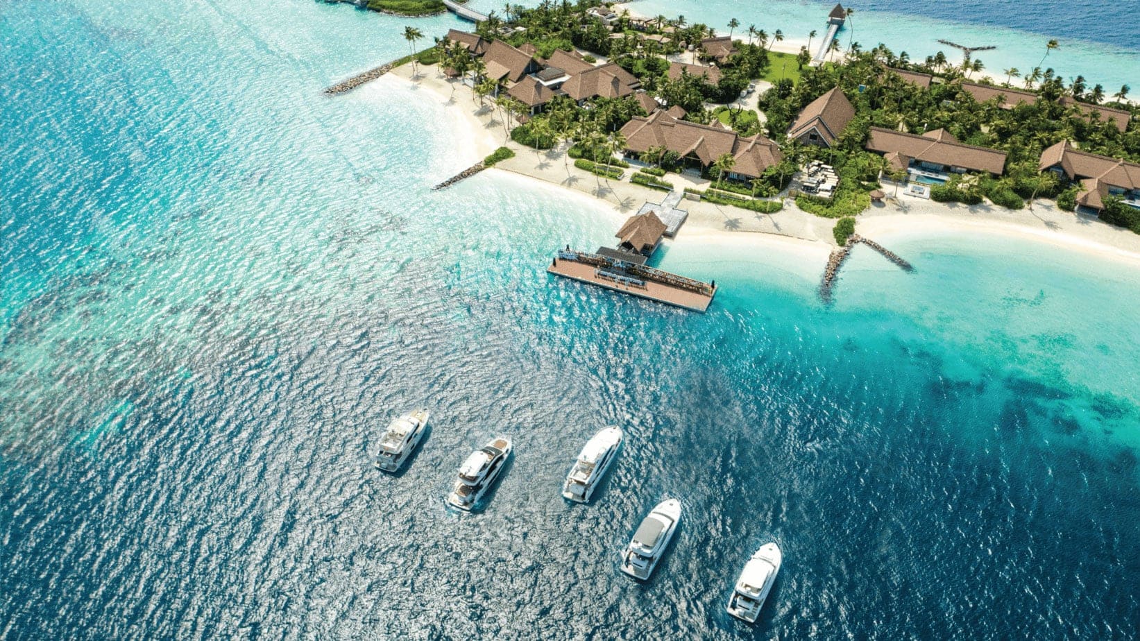 Bird view of island in Maldives called Waldorf Atoria Maldives Ithaafushi with suites, five yachts and private beatch.