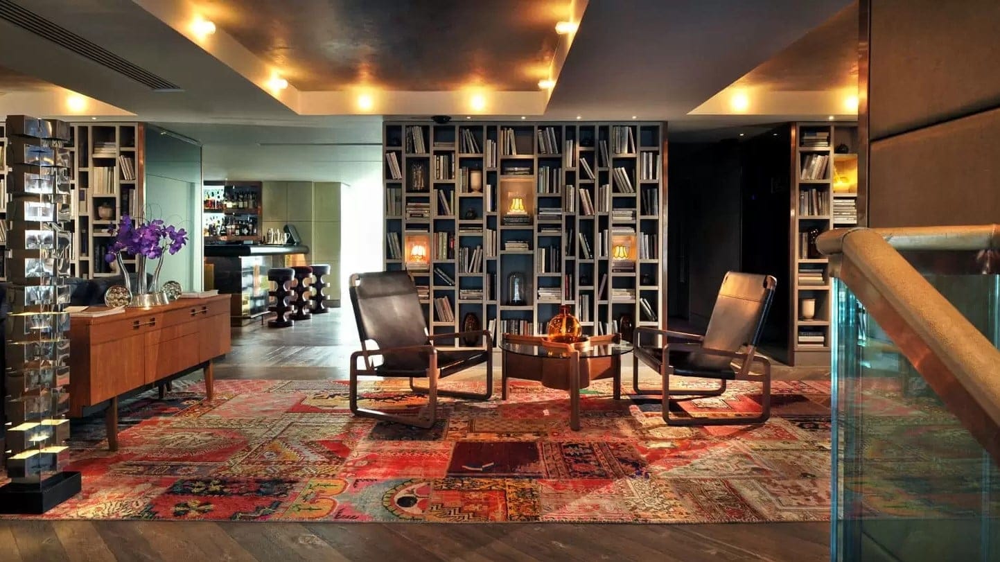 Reception at the hari london with a big bookshelf and brown desk