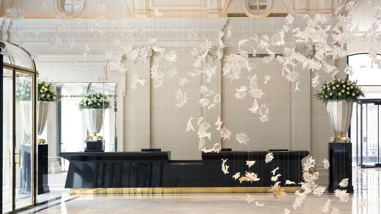Reception at The peninsula hotel paris with white walls and a big black and gold counter