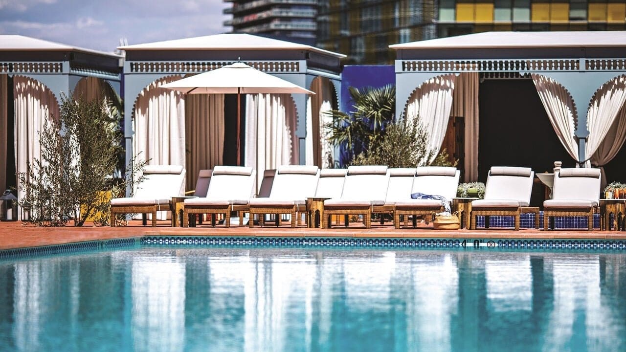 Pool area with white sunbeds, red floor, and white cubans at The NoMad Las Vegas.
