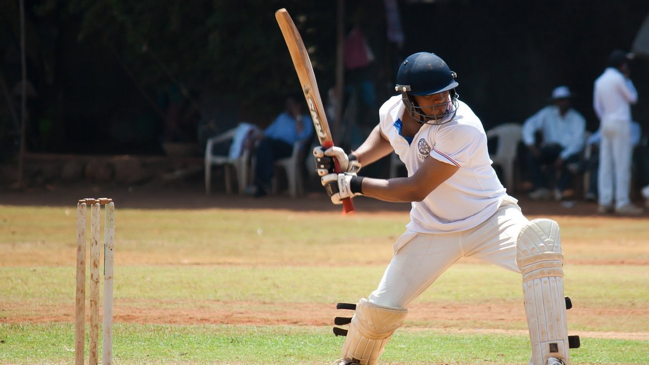 Man in white uniform and black suit hitting a cricket racket in Brabourne stadiumn