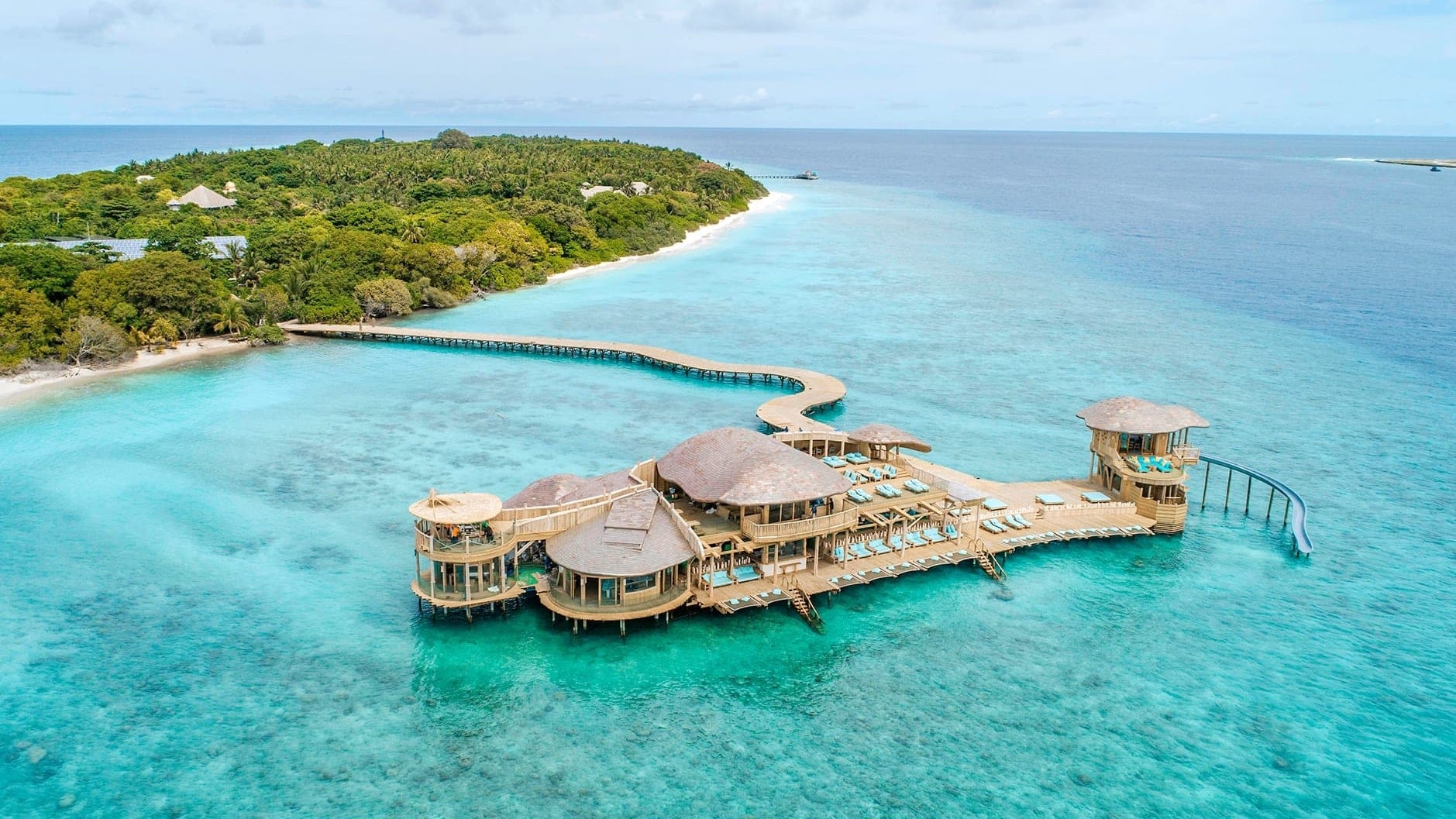 Bird view of large on water wodden building with water slider, sunbeds, and lunch area at Soneva Fushi, Noonu Atoll.