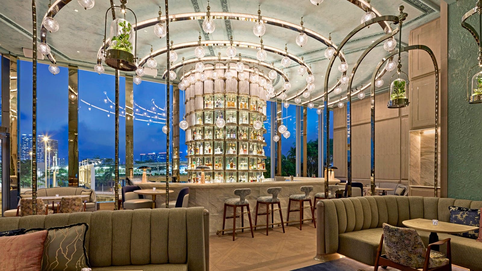Bar area and lounge at Four Seasons in Hong Kong with marble bar, green and white sofas and large windows to Hong Kong city.
