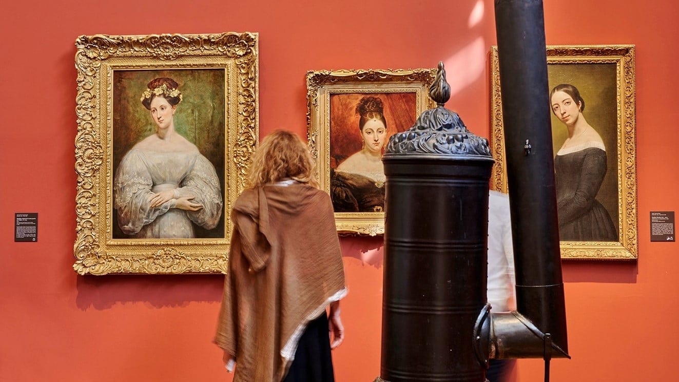 three paintings of women on a red wall in Musee de la Vie Romantique.