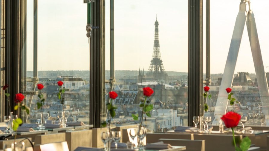 Cafe Georges Pompiduo with view of the Eiffel tower, red roses, and white decor.