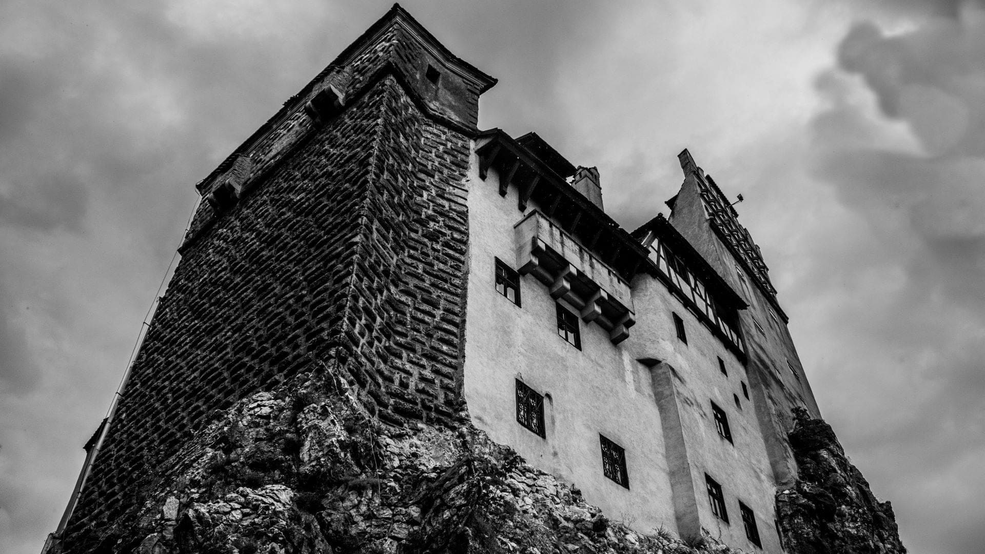 Castle bran in a white/black colour format, with brick, white sement, a few windows and cloudy sky in Transylvania.
