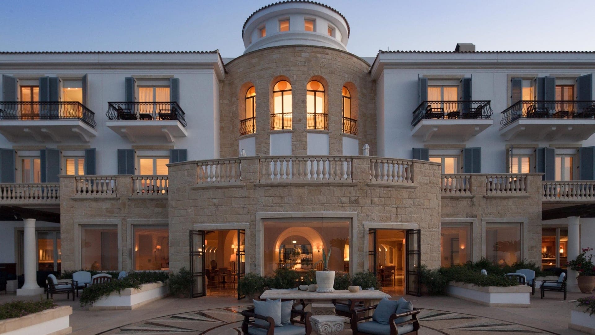 The Anassa hotel. A hotel with a big balcony, A seating area in the front.