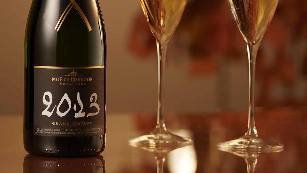 A MOET å CHANDON 2023 model at a table with two glasses