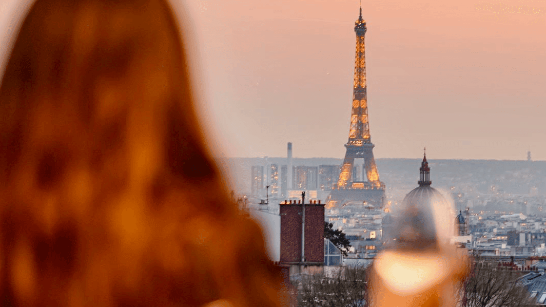 View of the Eiffel tower, behind a red haired woman at Le Rooftop, Terrass Hotel.