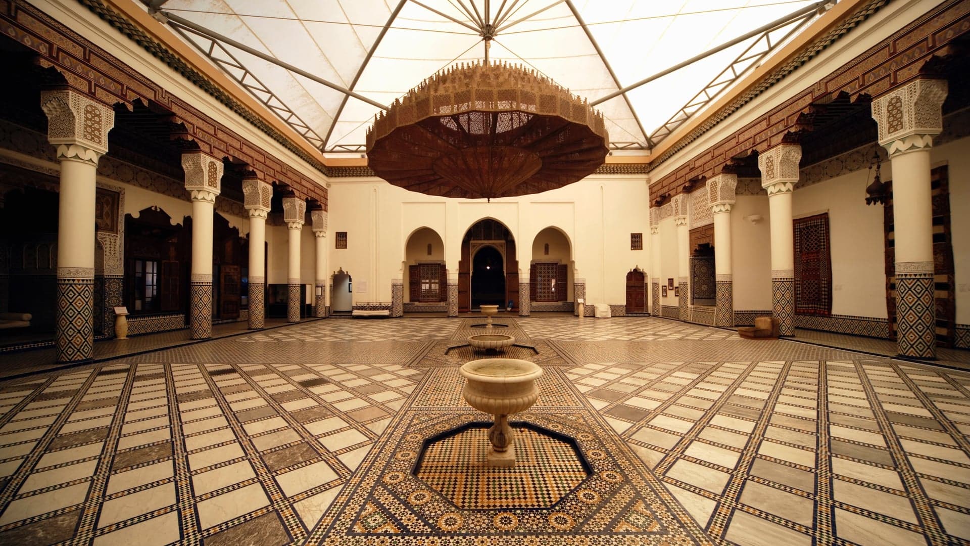 Musée de marrakech with a big brown lantern hanging from the celeing. White glass roof, white walls withn white collums.
