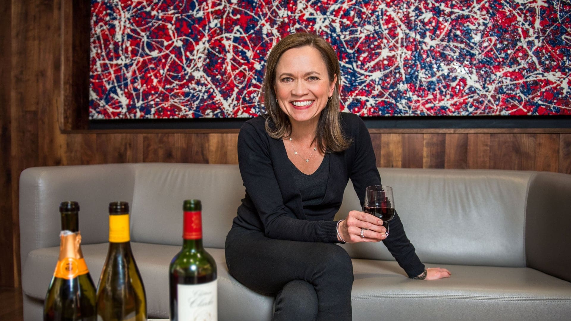 A woman smiling with a wine in her hand on a businessclass lounge