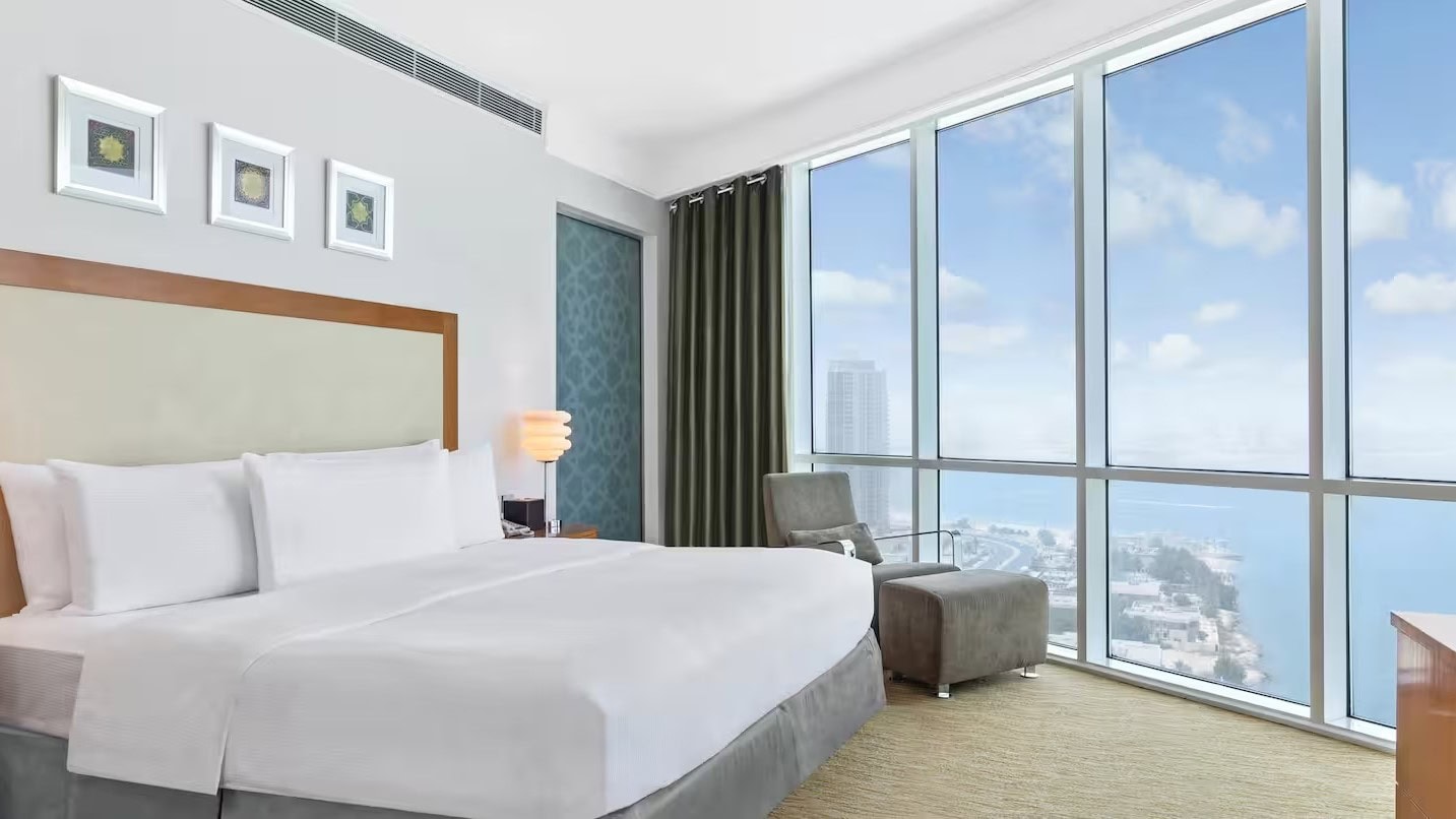 a room with large windows beside a bed at Hilton Doha