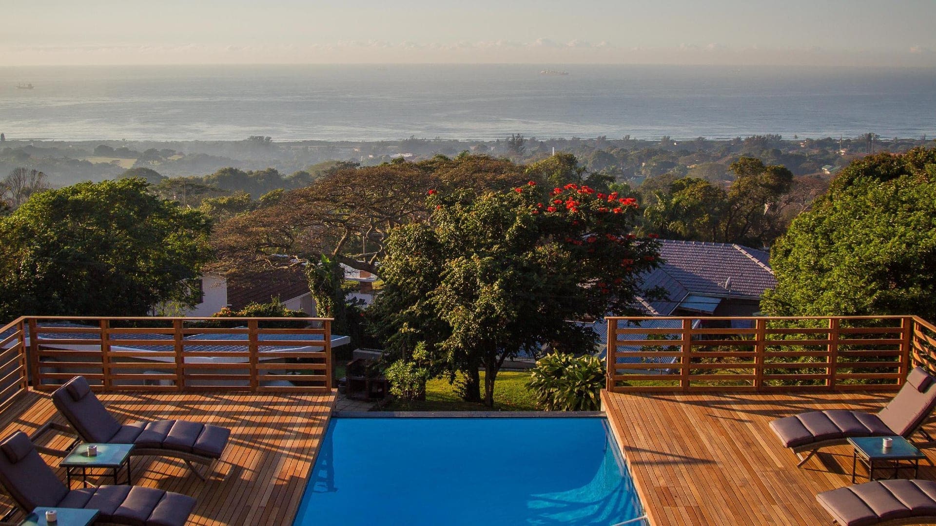 Rooftop pool area with view of woods and the ocean at Endless Horizons Boutique Hotel
