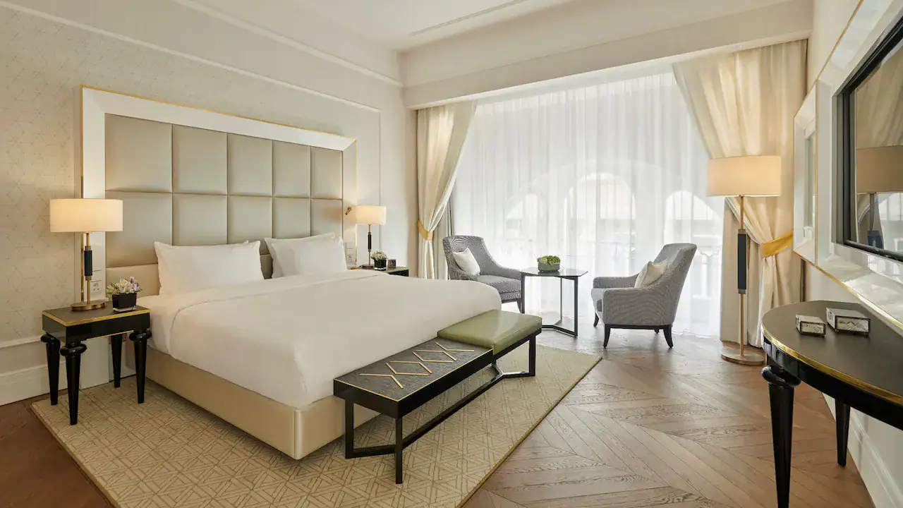 Hotel room at Parisi Udvar Hotel Budapest with kingsize bed, wooden floor and grey chairs.