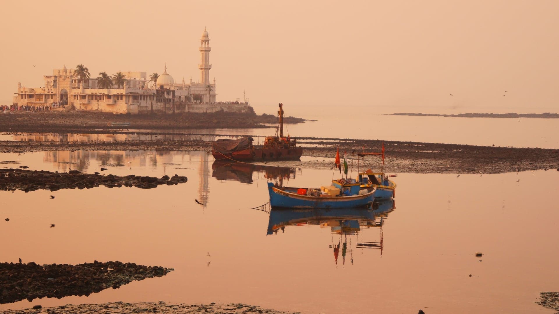 Small lake with blue boats, white palace in the backround at Hail Ali Dargagh Mosque.