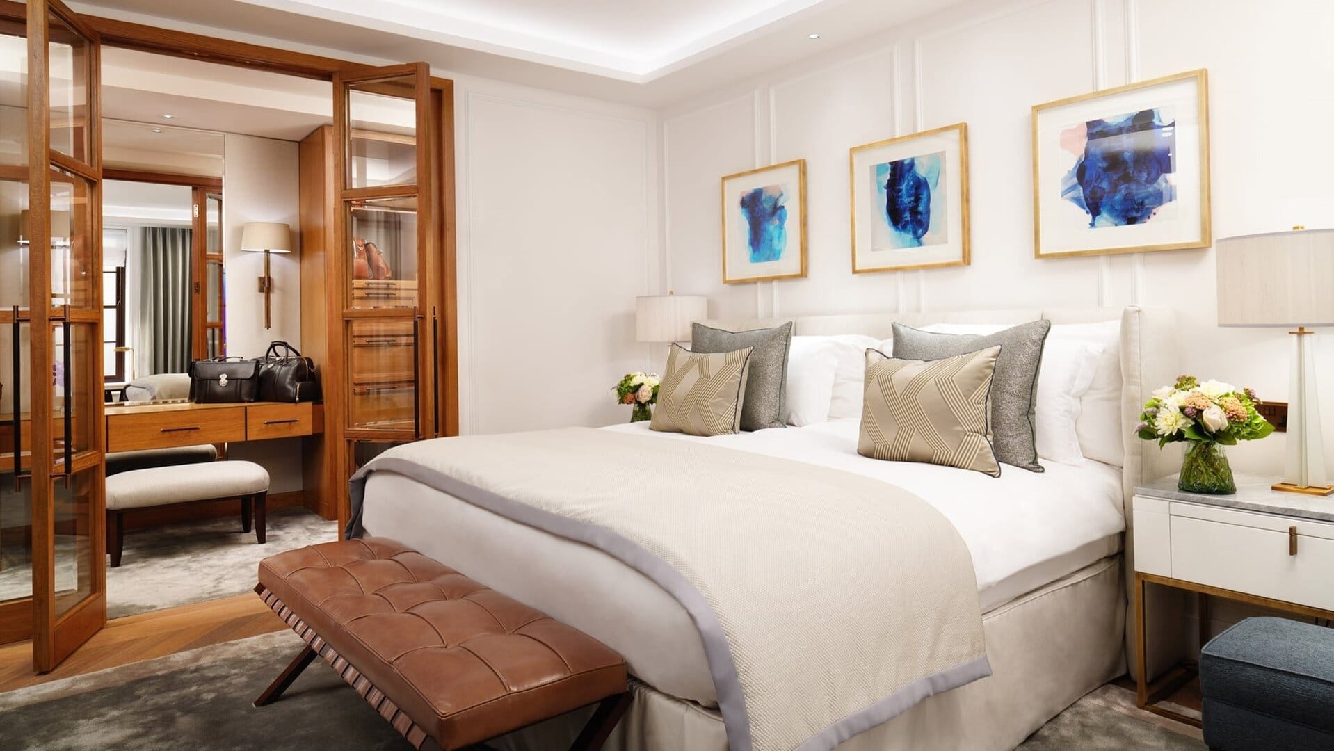 A suite with a king sized bed with three painting above at Corinthia london