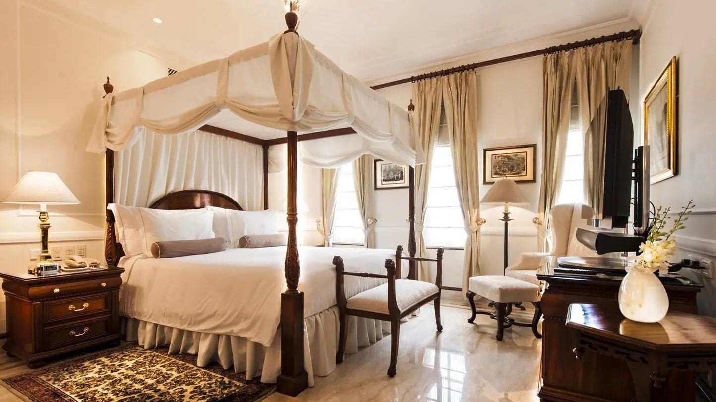 Bedroom with white bed, wooden furniture and marble floor at The Imperial Delhi