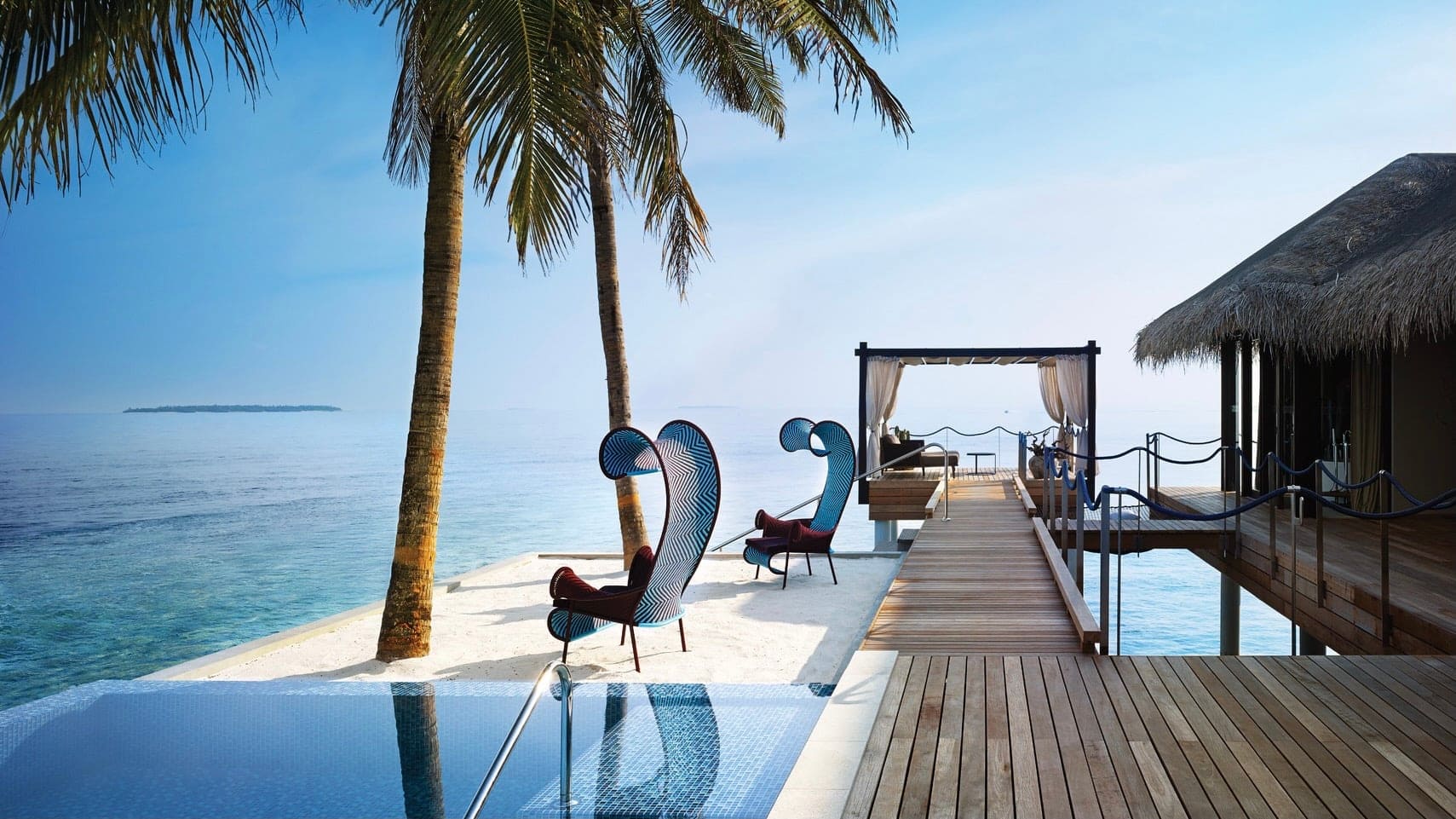 Pool, chairs, cabin suite, and crystal clear water at Velaa Private Island.